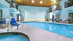 An indoor swimming pool with blue chairs and a small hot tub area. - Days Inn & Suites by Wyndham Albuquerque West (Albuquerque)