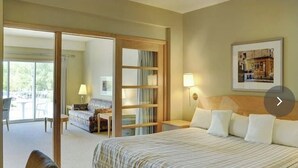 A hotel room with a bed, a desk, a chair, a sofa, a sliding glass door leading to an outdoor area, and a framed picture on the wall. - One Bedroom for Icelandic Festival week (Gimli)