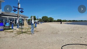 A beach area with a building, a lighthouse, and a parking area. - One Bedroom for Icelandic Festival week (Gimli)