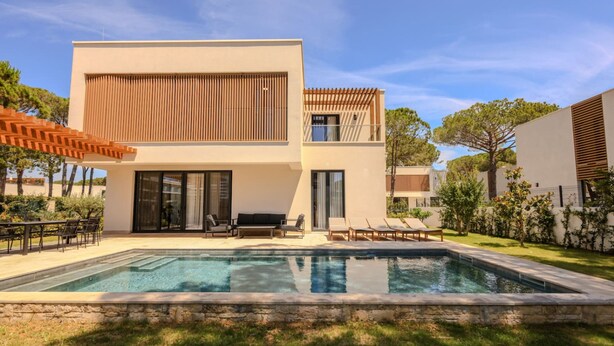A modern two-story house with a swimming pool, outdoor seating, and a pergola.