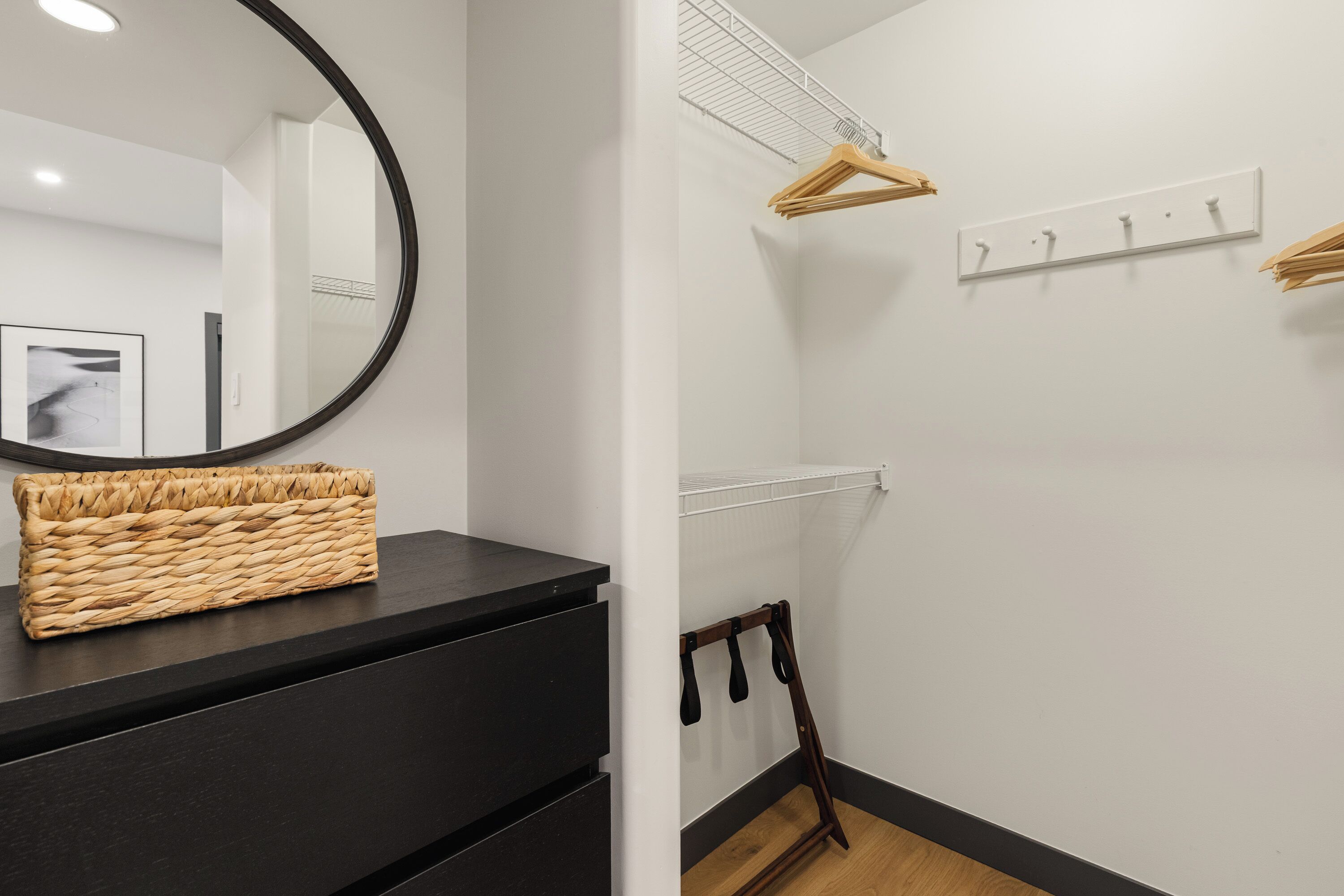 A modern bathroom with a black vanity, a round mirror, and a wicker basket.