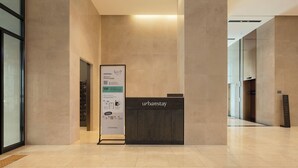 Un área de recepción con un mostrador oscuro, un cartel con información y una decoración de diseño moderno.