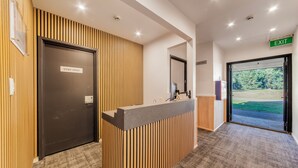 A reception area with a 'STAFF ONLY' door, a reception desk, and an 'EXIT' sign. - Harewood Lodge (Christchurch)