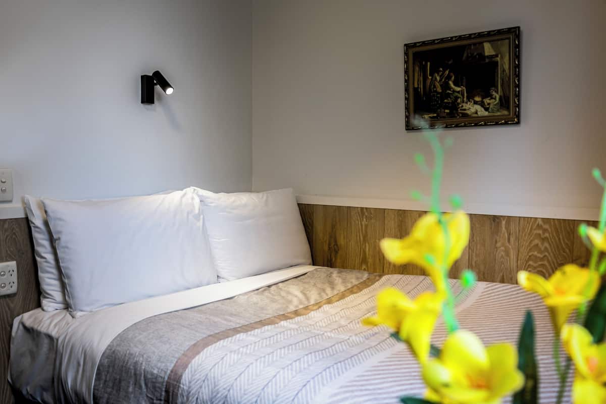Ein Hotelzimmer mit Bett, Wandleuchte und einem gerahmten Bild.