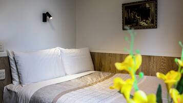 Una habitación de hotel con una cama, una lámpara de pared y un cuadro enmarcado.