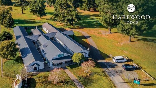An aerial view of a lodge with multiple buildings, surrounded by trees and a golf course. - Harewood Lodge (Christchurch)