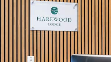 A reception desk with a sign reading "Harewood Lodge" against a wooden slat wall.
