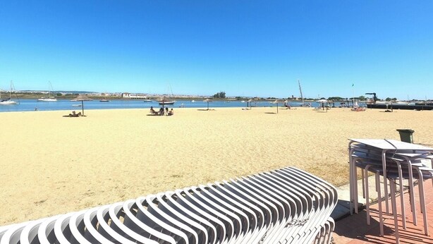 A beach with a clear sky, a sandy shore, and a few boats in the water.