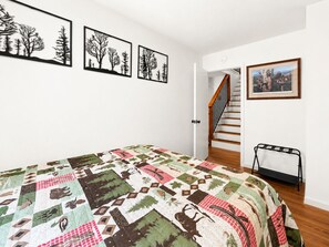 Un dormitorio con cama, una escalera y una puerta que da a otra habitación.