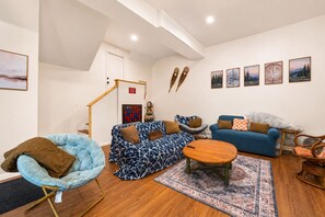 Un salon moderne avec un canapé bleu, un fauteuil à motifs, une table basse en bois et un tapis.
