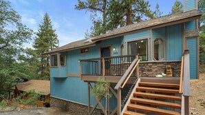 A two-story house with a blue exterior, a stone staircase, and a wooden deck.