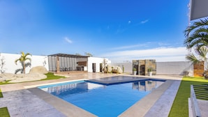 A modern pool area with a rectangular pool, surrounded by a patio with artificial grass and a stone wall. - Quiet and elegant place in Cabo (Cabo San Lucas)
