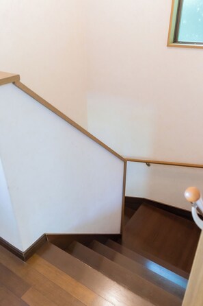 Una escalera de madera con barandilla y una lámpara en la parte superior.