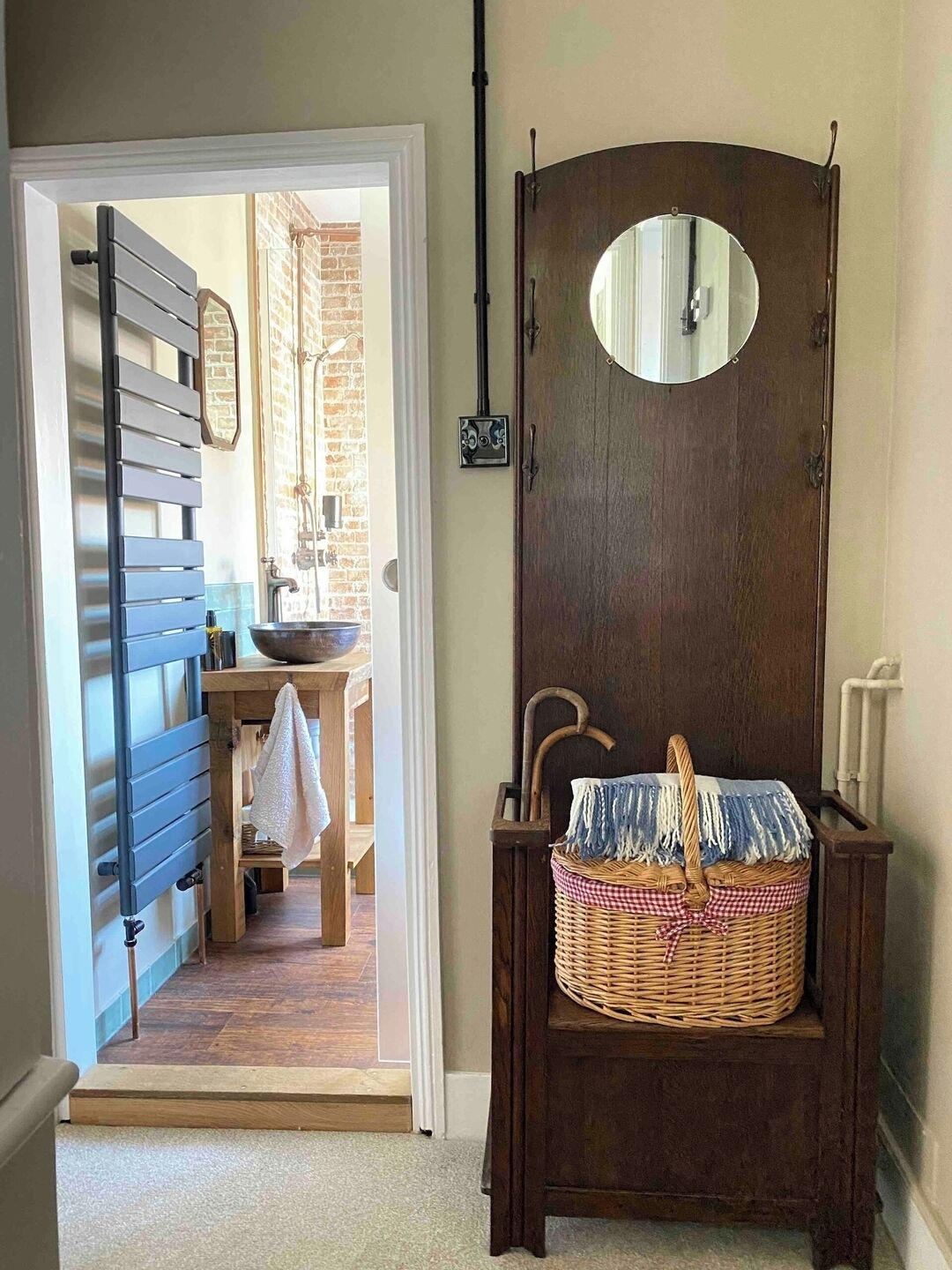 A bathroom with a wooden door, a mirror, and a wicker basket.