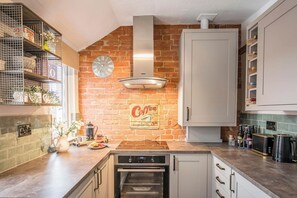Een koelkast, een oven, een vaatwasser, kookgerei, borden en bestek