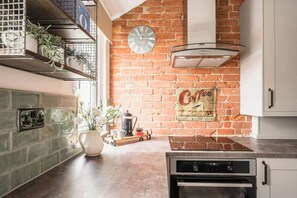 Een koelkast, een oven, een vaatwasser, kookgerei, borden en bestek