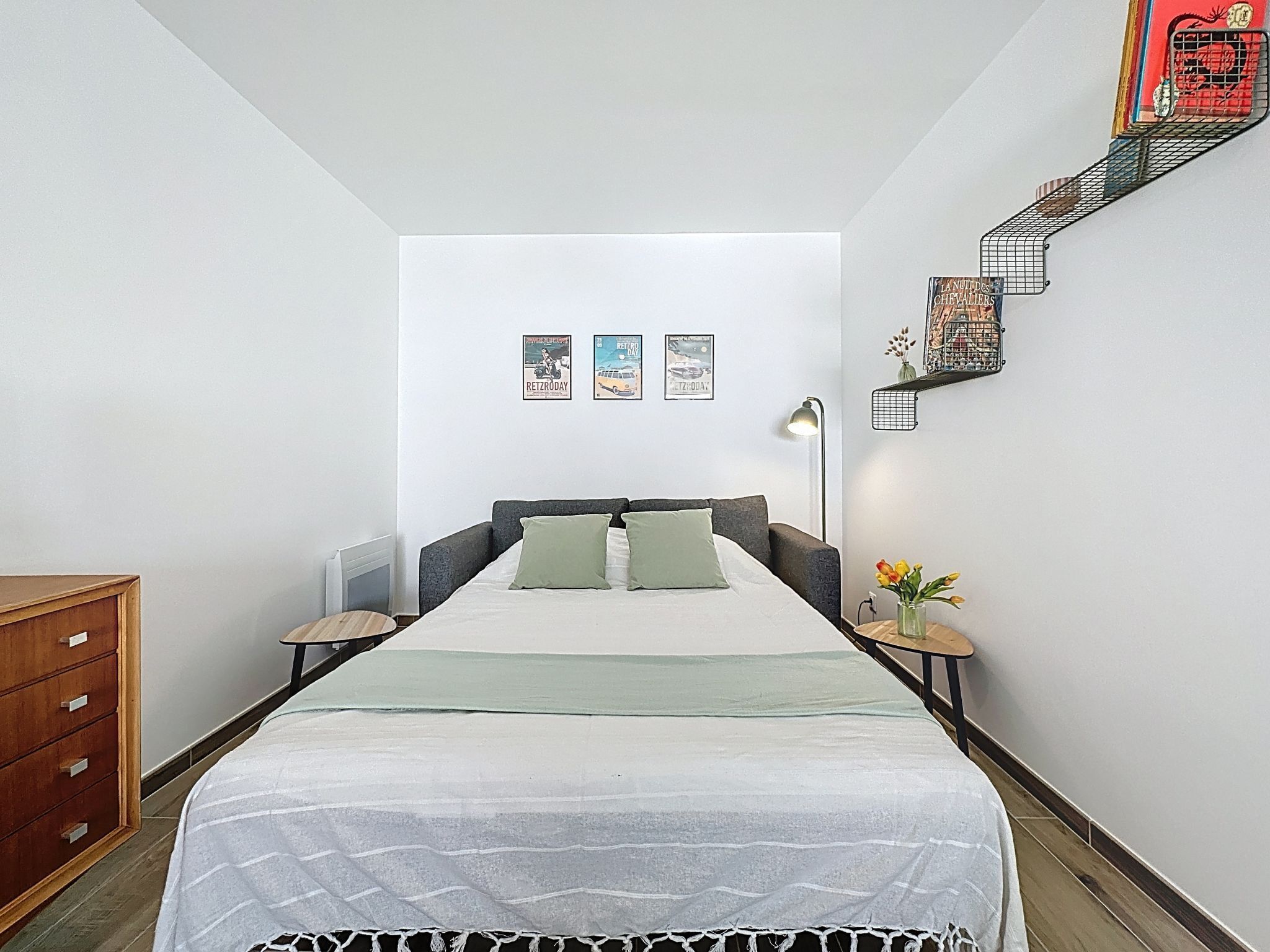 Un dormitorio minimalista con cama, mesitas de noche, cómoda y decoración en la pared.