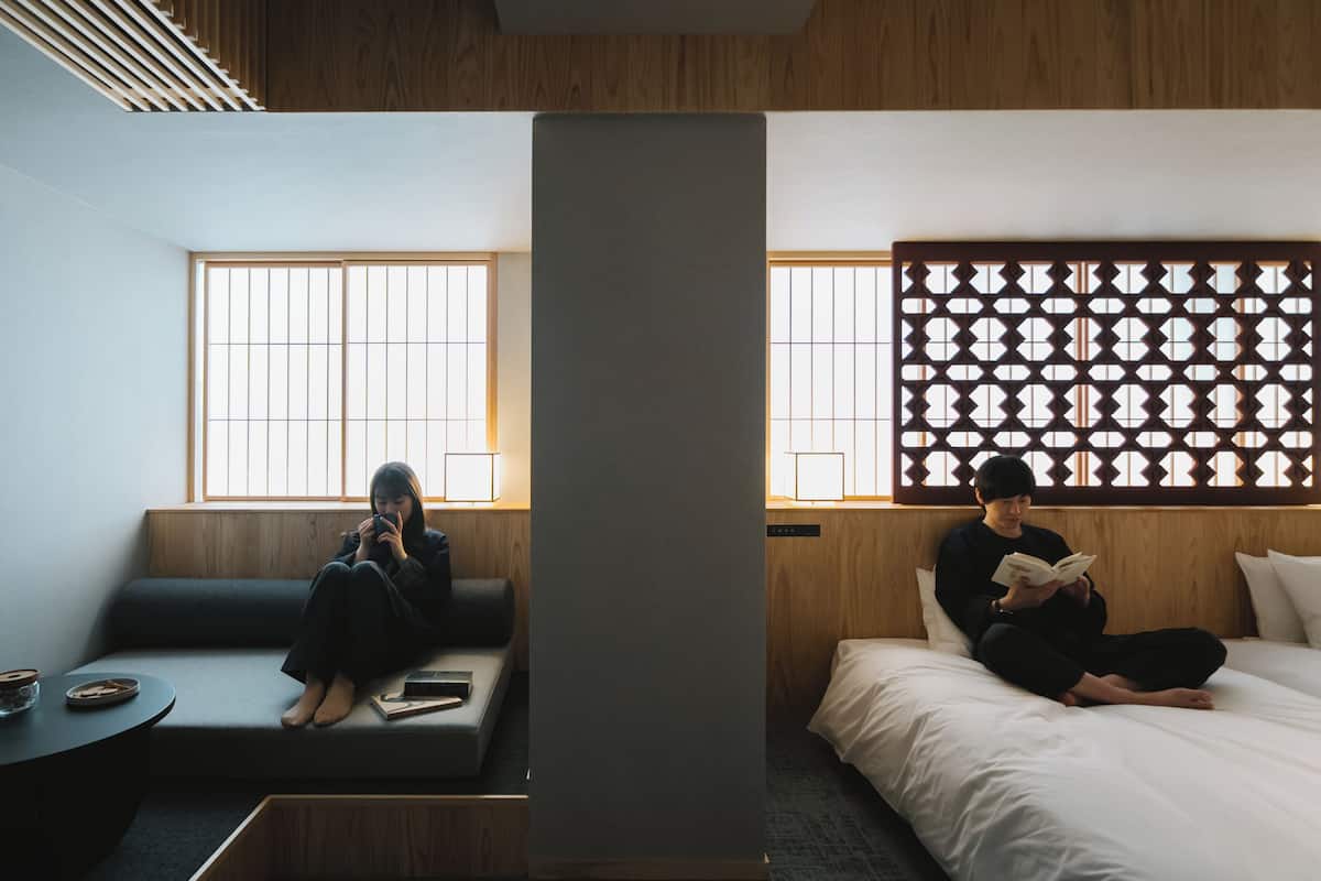 A hotel room with a sofa and a bed, both with wooden headboards.