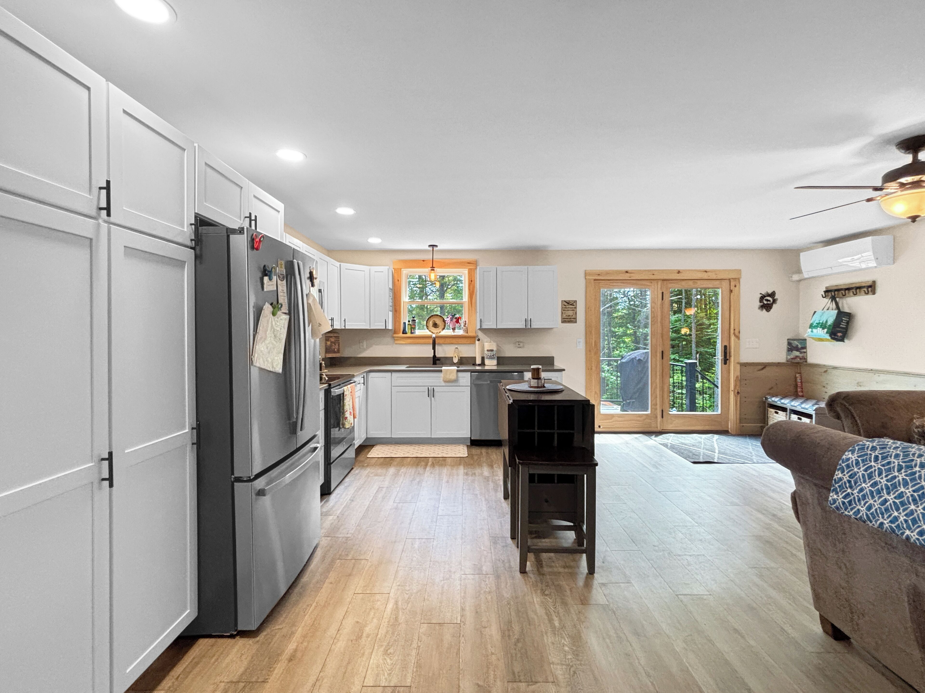 A modern kitchen with white cabinets, a stainless steel refrigerator, and a wooden dining table.