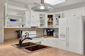 A modern kitchen with white cabinetry, a double sink, a stove, and a refrigerator.