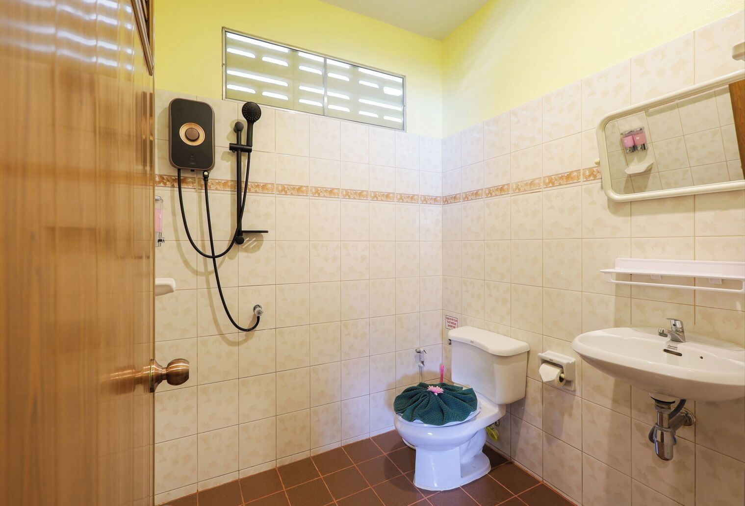 A bathroom with a toilet, sink, shower, and a towel rack.
