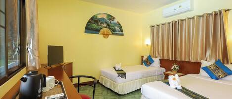 A hotel room with two beds, a desk with a kettle, a chair, a painting on the wall, and an air conditioning unit.