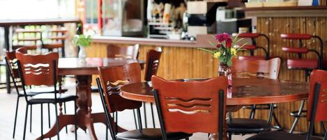 Ein Restaurant mit Holztischen und -stühlen, einer Bar und einem Blumenstrauß auf dem Tisch.