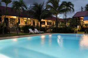 A swimming pool with lounge chairs, surrounded by palm trees and a building with a red roof. - The Gold-Digger's Resort (Sa Khu)