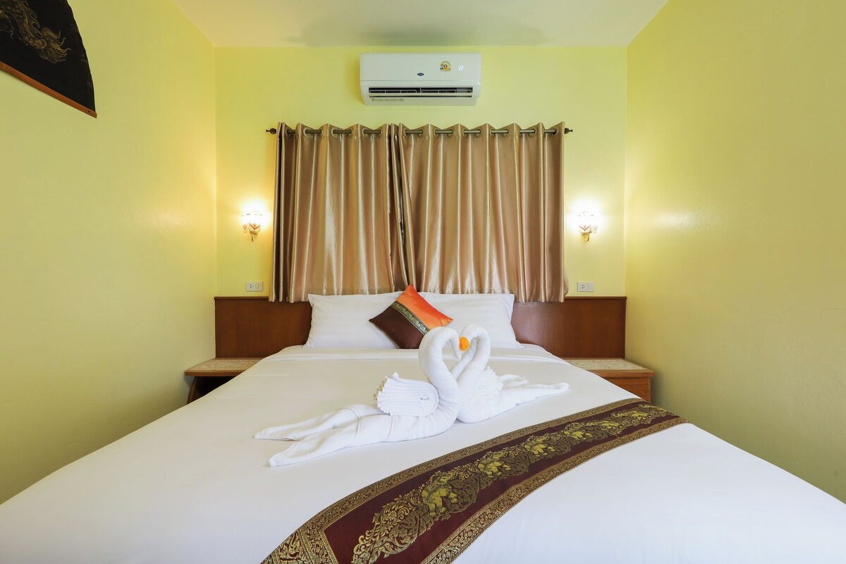 Une chambre d’hôtel avec un lit, des rideaux, un climatiseur et une disposition décorative des serviettes.