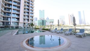 A rooftop pool with lounge chairs and a high-rise building in the background.