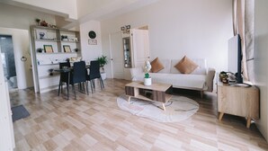 Ein modernes Wohnzimmer mit einem weißen Sofa, einem Couchtisch und einem Essbereich mit Stühlen und einem kleinen Tisch.