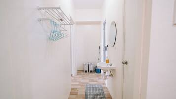 A narrow hallway with a white sink, mirror, and towel rack.