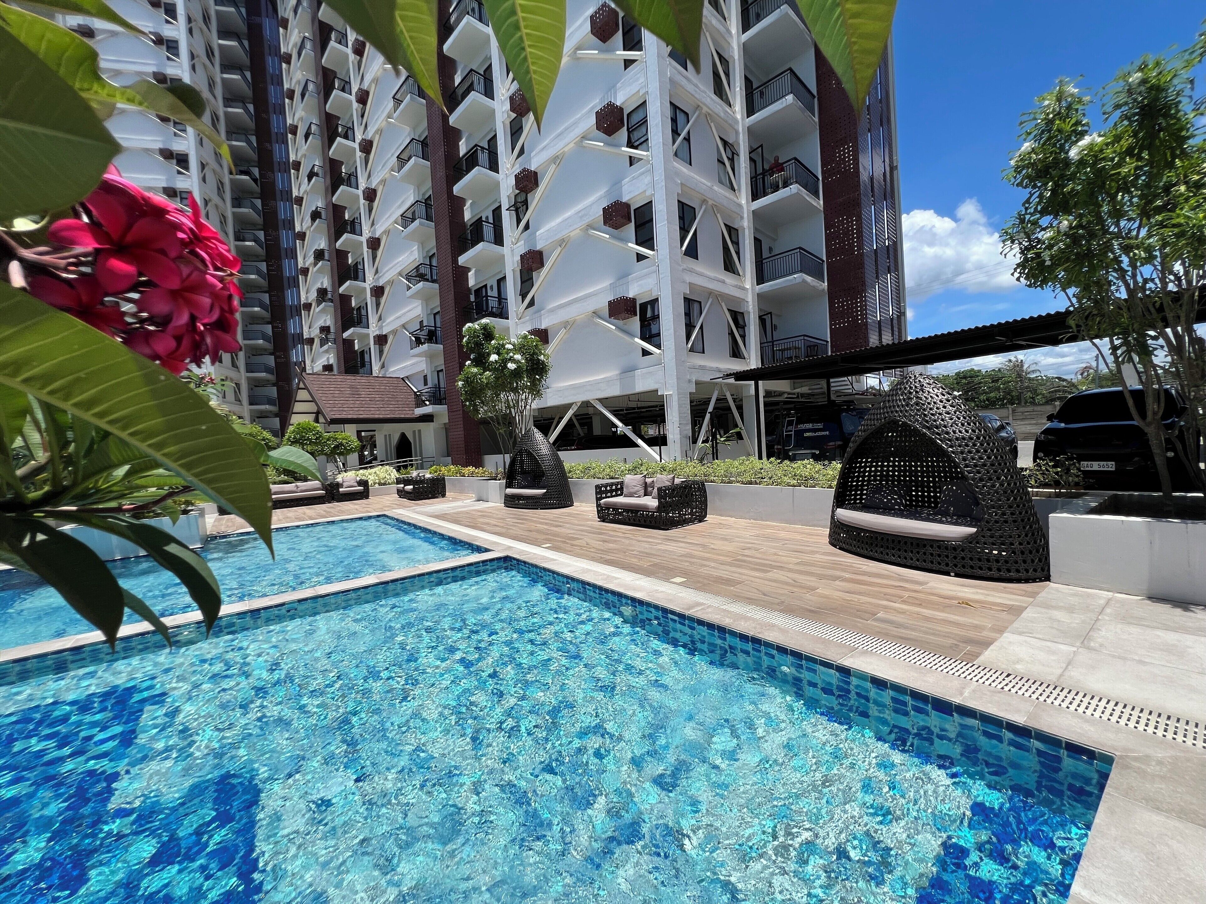 A swimming pool with lounge chairs and a building with balconies in the background.