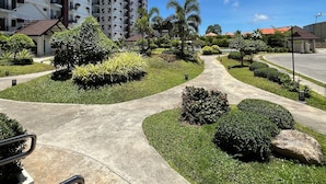 A residential area with a curved pathway, well-maintained greenery, and tall buildings in the background. - APARTMENT IN LAPU-LAPU CITY RESORT TYPE-Near Mactan Airport 60 SQM.WITH 2BR (Lapu-Lapu)