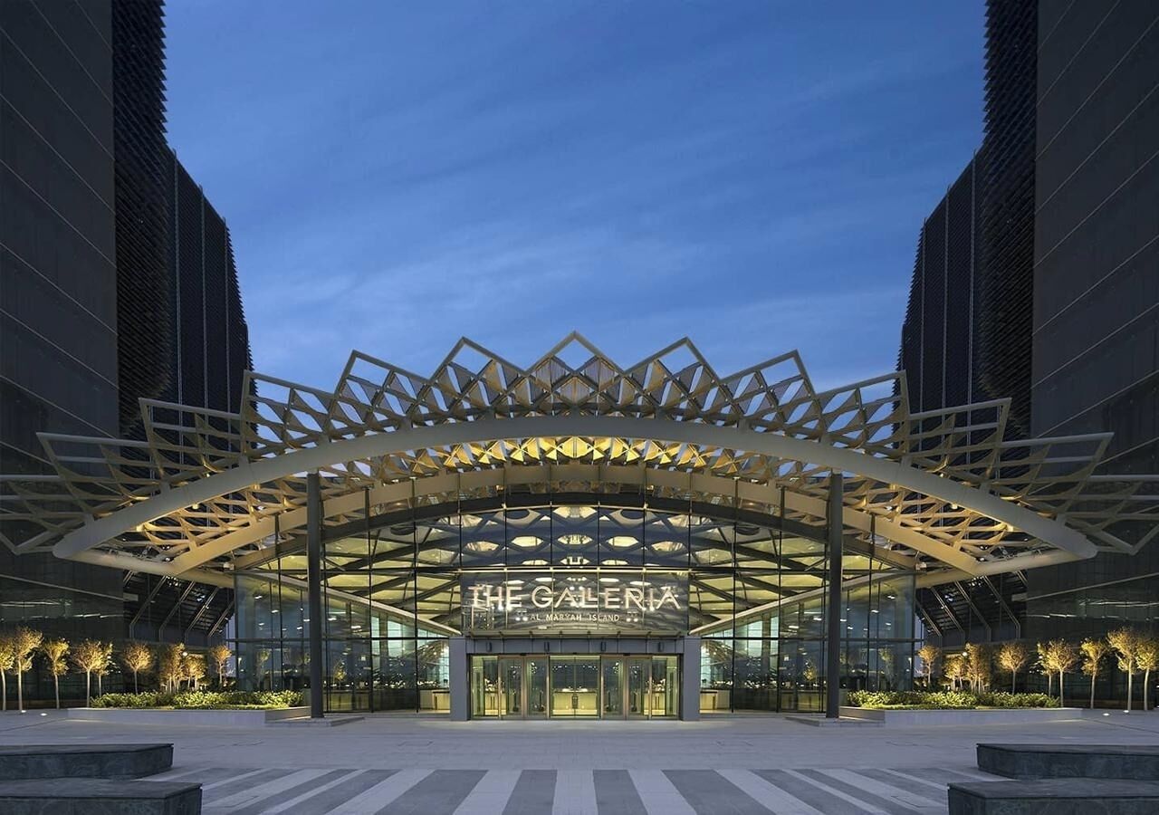A modern building with a glass facade and a distinctive geometric roof structure.