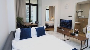 A hotel room with a large bed, a TV, a desk, and a bathroom.