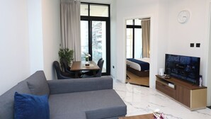A modern living room with a sofa, dining table, TV, and a view of the city.