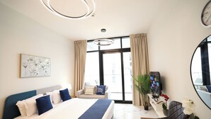 A modern hotel room with a large bed, a desk with a TV, a chair, and a large window. - City-Linked Studio near Galleria and Cleveland (Abu Dhabi)