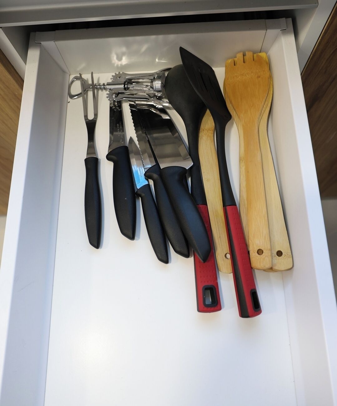 Un cajón con varios utensilios de cocina, incluyendo cuchillos, un rallador y una espátula de madera.