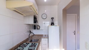 A compact kitchen with a gas stove, a sink, a blender, and a clock on the wall. - Apto 1 Quarto no centro em Itajaí CST0905 (Itajai)