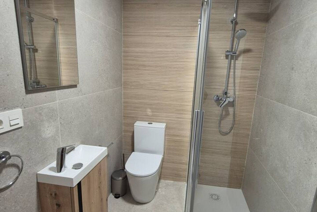 Une salle de bain moderne équipée d’une douche, de toilettes, d’un lavabo et d’un miroir.