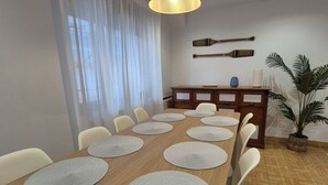 Ein Essbereich mit einem langen Holztisch, weißen Stühlen und runden Tischsets.