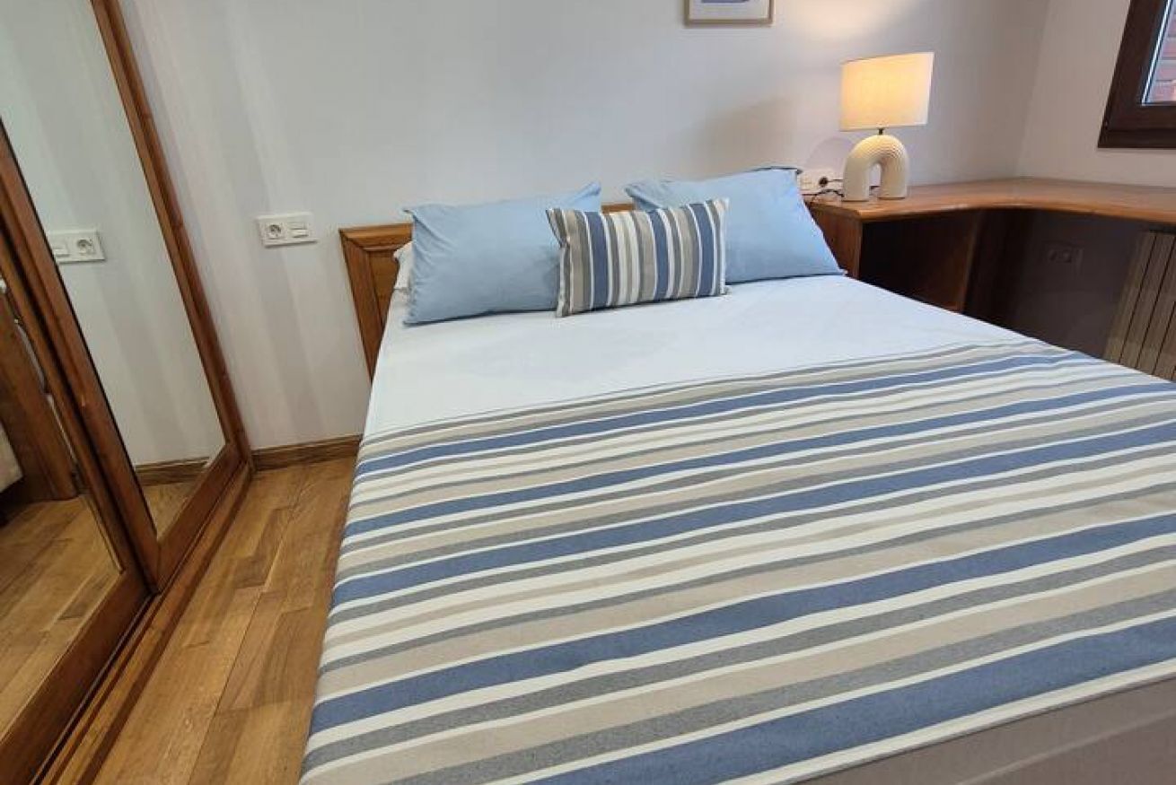 Hotellihuone, jossa on sänky, yöpöytä, lamppu ja puulattia.