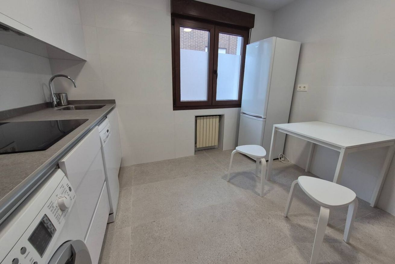 Cocina compacta con lavadora, un lavabo, una ventana y una pequeña mesa.