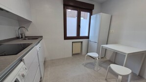 Eine kleine Küche mit Waschmaschine, Spüle, Fenster und einem kleinen Tisch.