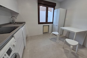 Cocina compacta con lavadora, un lavabo, una ventana y una pequeña mesa.