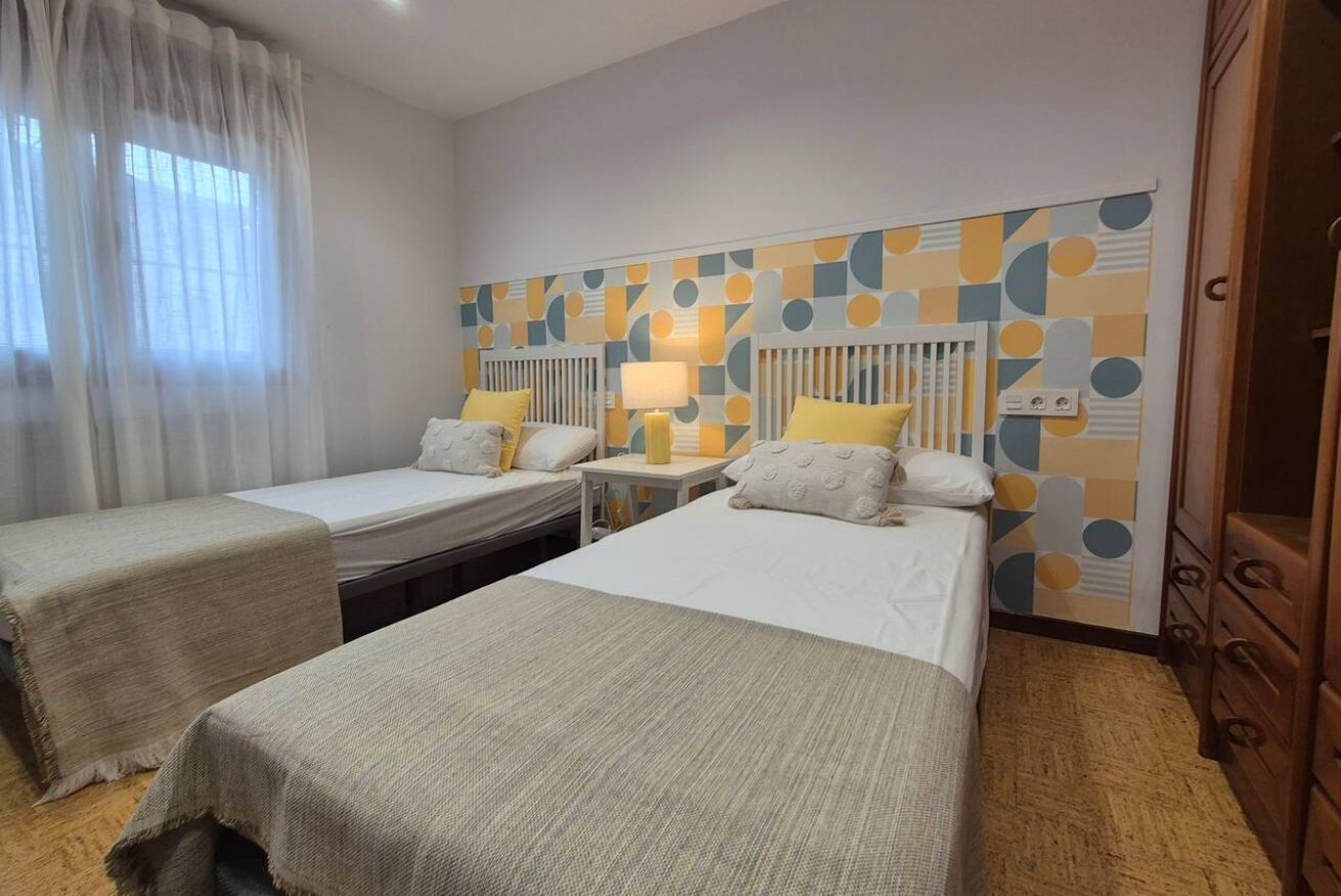 Una habitación de hotel con dos camas individuales, una mesita de noche con lámpara, un radiador y un armario.