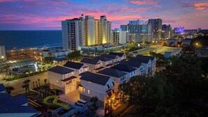 A coastal hotel with multiple high-rise buildings, a marina, and a well-lit urban area at dusk.