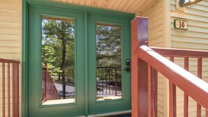 A green door with a number "30" on the wall, a wooden porch, and a metal railing.