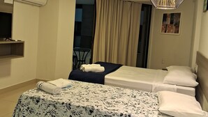 Une chambre d’hôtel avec un lit, un luminaire au plafond, un climatiseur et une fenêtre avec des rideaux.